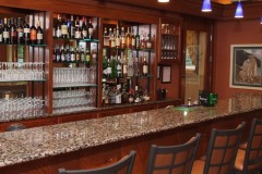 Bar with granite top in front of barstools and large assortment of alcohol under purple lights at The Inn at Ohio Northern University in Ada, OH