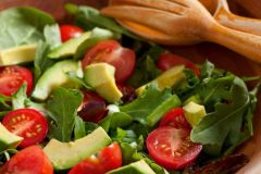 Green salad with lettuce, spinach, tomatoes and avacados in wooden bowl near wooden spoon at The Inn at Ohio Northern University in Ada, OH