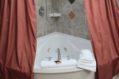 Jetted spa bathtub with red shower curtains and white towels at The Inn at Ohio Northern University in Ada, OH