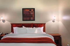 Large bed with white linens and red blankets with pillows and modern artwork on the walls at The Inn at Ohio Northern University in Ada, OH