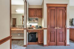 Kitchenette with mini fridge, sink and microwave next to bathroom entrance and closet space