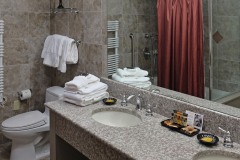 Granite bathroom fixtures with soaps and towels on top of sink in front of red shower curtain at The Inn at Ohio Northern University in Ada, OH