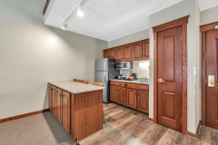 Granite countertop with bar stools near refrigerator and microwave with coffeemaker and wooden cabinets at The Inn at Ohio Northern University in Ada, OH