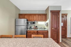 Granite countertop with bar stools near refrigerator and microwave with coffeemaker and wooden cabinets at The Inn at Ohio Northern University in Ada, OH