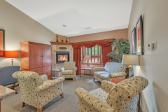 Group of chairs and sofas arranged in circle near side table and lamps in front of red curtains and stone fireplace at The Inn at Ohio Northern University in Ada, OH