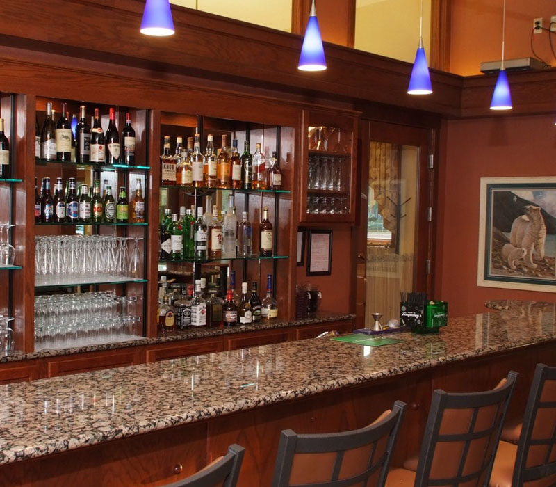 Bar with granite top in front of barstools and large assortment of alcohol under purple lights at The Inn at Ohio Northern University in Ada, OH