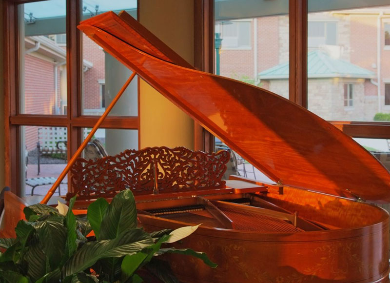 Grand wooden piano near green plant open near window at The Inn at Ohio Northern University in Ada, OH