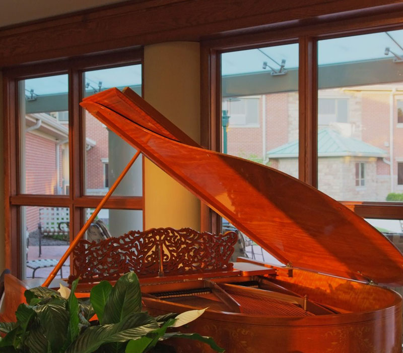 Grand wooden piano near green plant open near window at The Inn at Ohio Northern University in Ada, OH